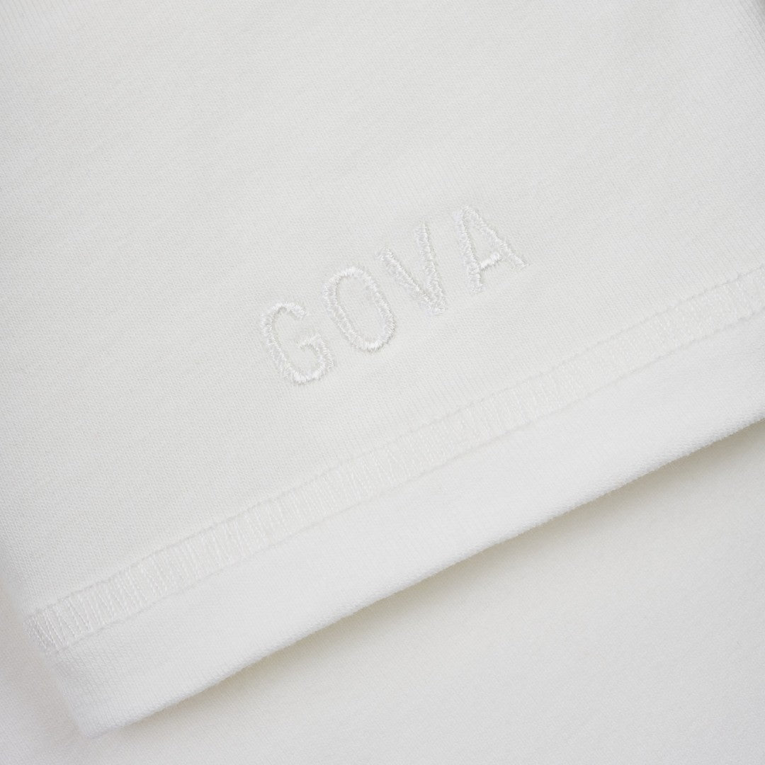 Close up of white embroidered logo on the sleeve of a women's cotton t-shirt.