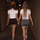 Two girls walking down a dimly lit hallway holding hands.
