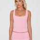 Blonde model wearing a bright pink vest top and bright pink mini skirt standing with hands by side.