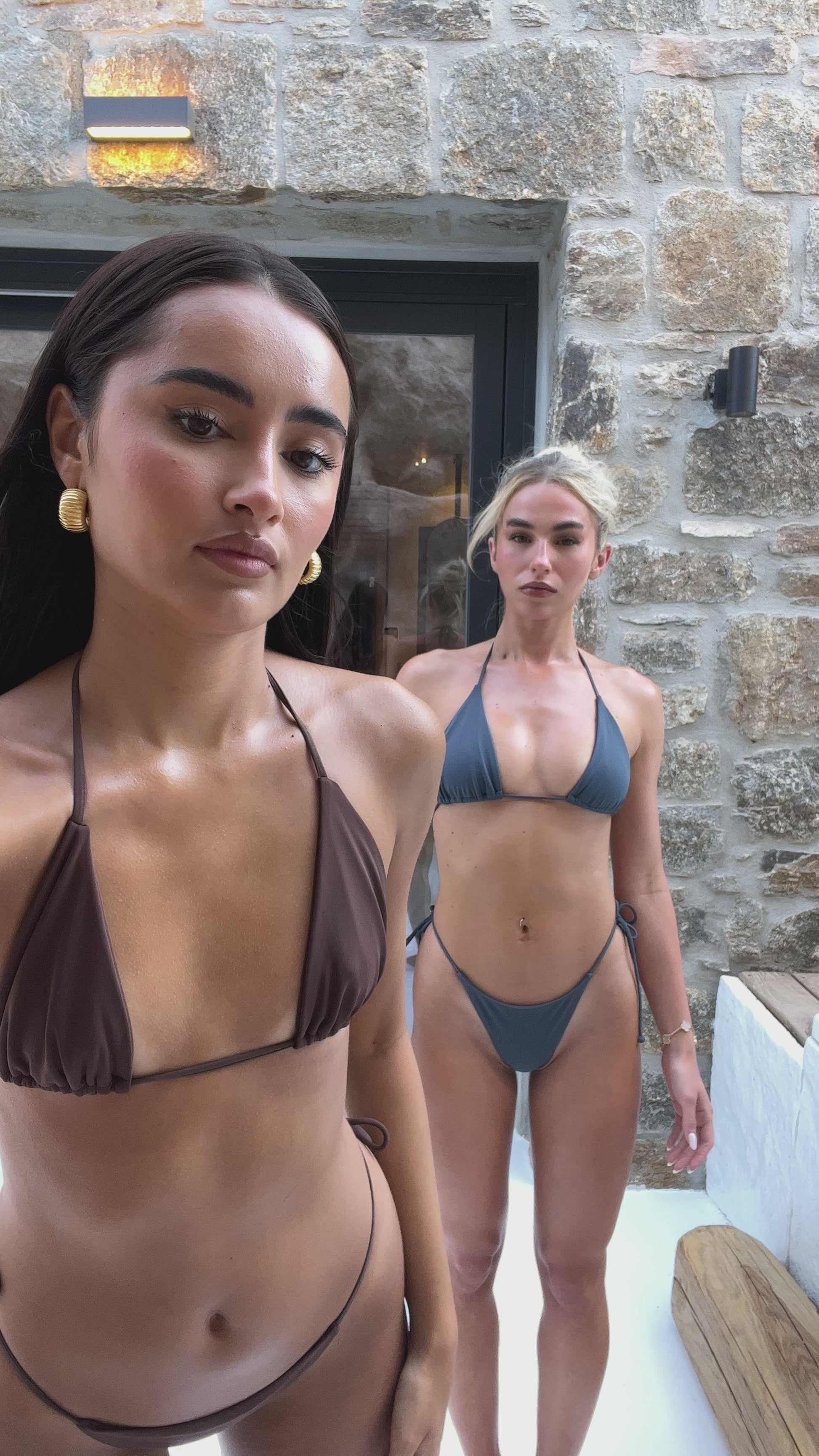 Models wearing dark brown bikini and navy blue string bikini.